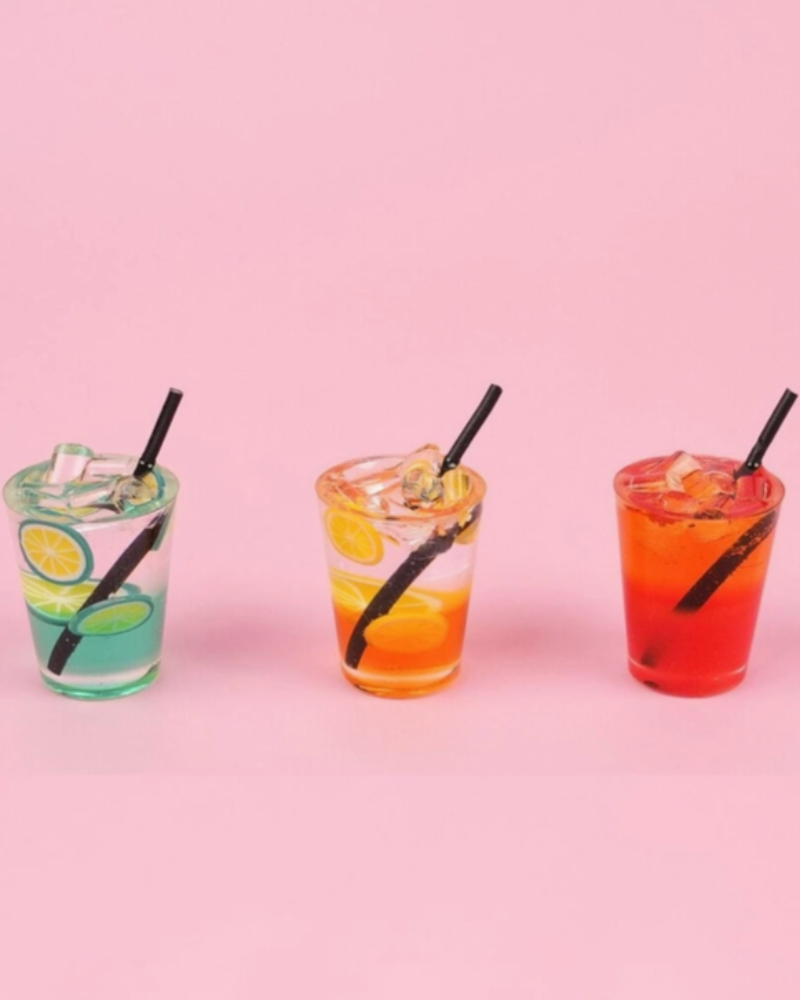 Three glasses of iced drinks with straws on a pink background