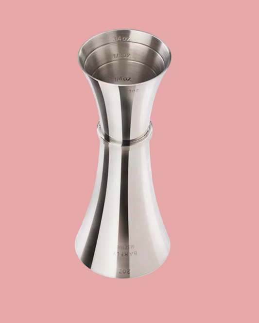 Stainless steel jigger on a pink background