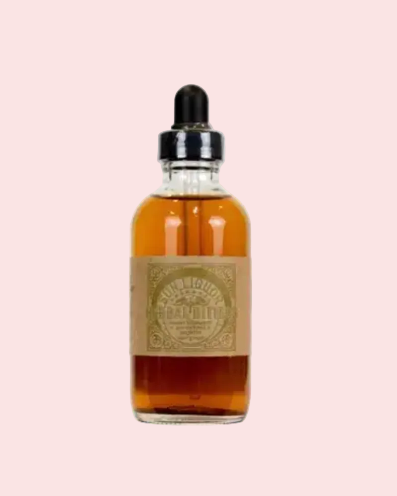 Dropper bottle of Sun Liquors bitters on pink background