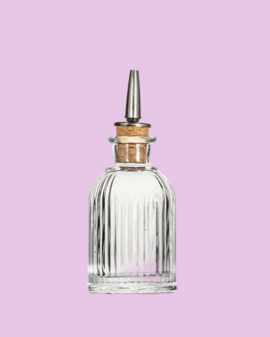 Clear glass bottle with wooden cap on a pink background