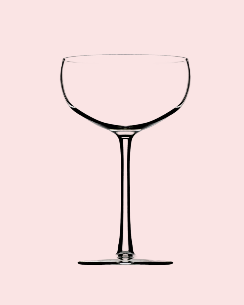 Clear glass cocktail coupe on a pink background