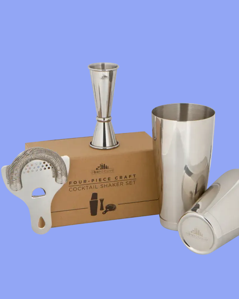 Four-piece craft cocktail shaker set with jigger, tumblers, and strainer on a white background.