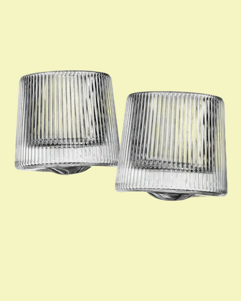 Two ribbed glass wall sconces on a light yellow background
