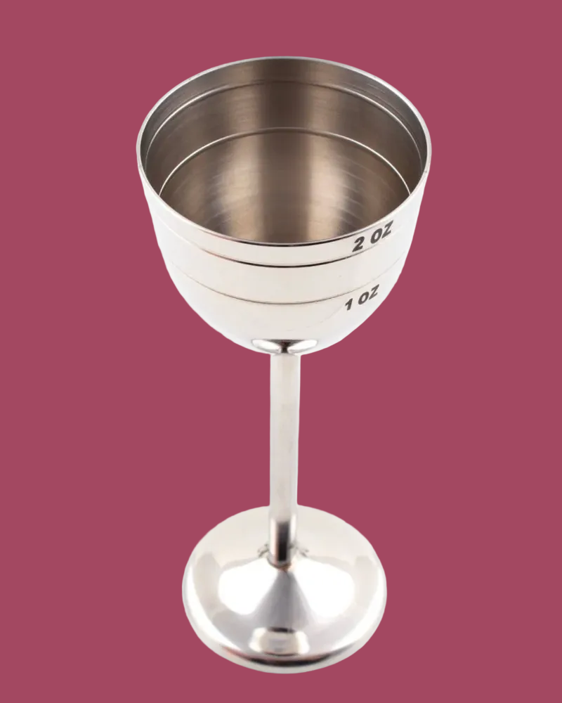 Silver measuring cup with markings on a pink background