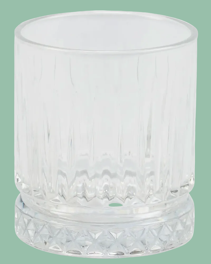 Clear glass tumbler with textured design on a green background