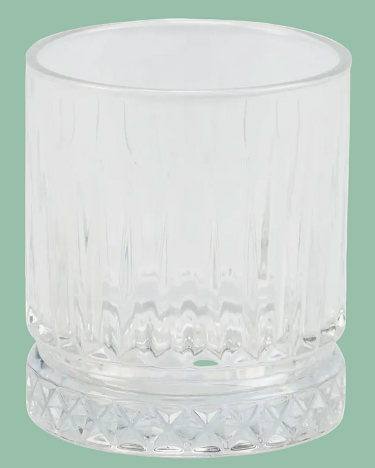 Clear glass tumbler with textured design on a green background