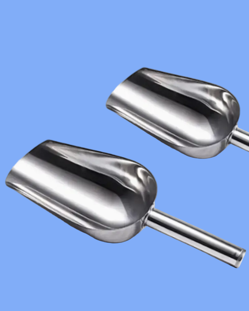 Two metal scoops on a white background with a small pile of spices.