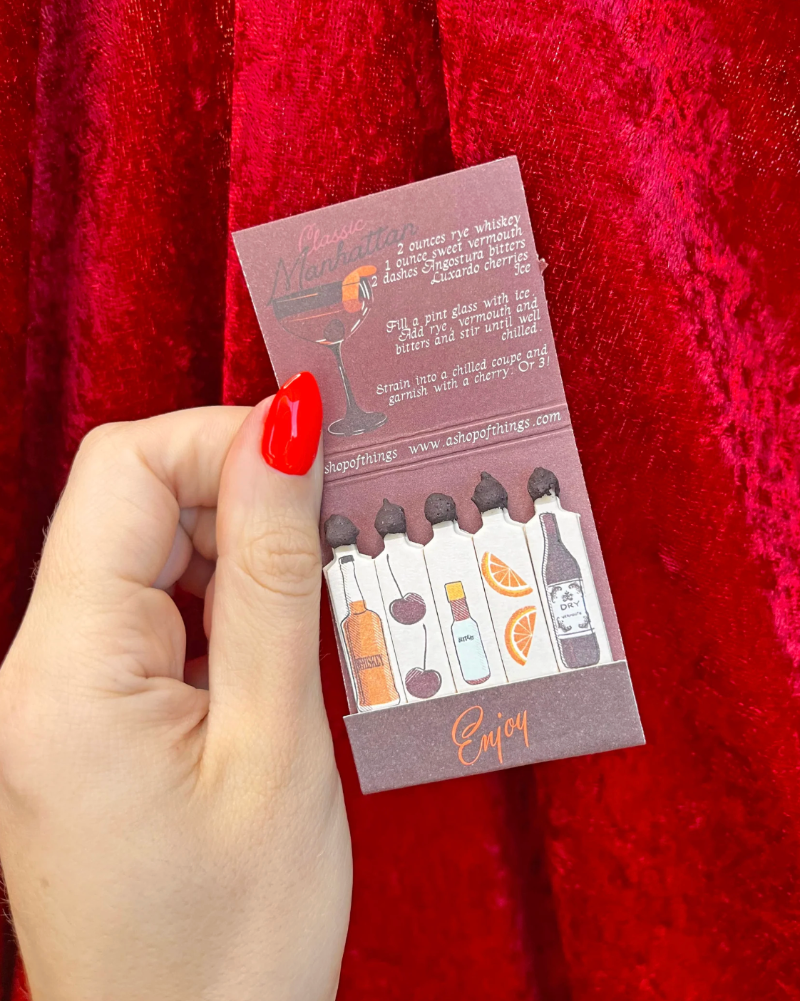 Hand holding a small product packaging with text and illustrations against a red background