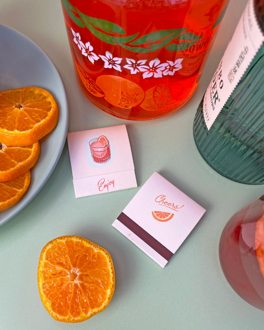 Bottles of orange juice and a plate with orange slices on a light green surface.