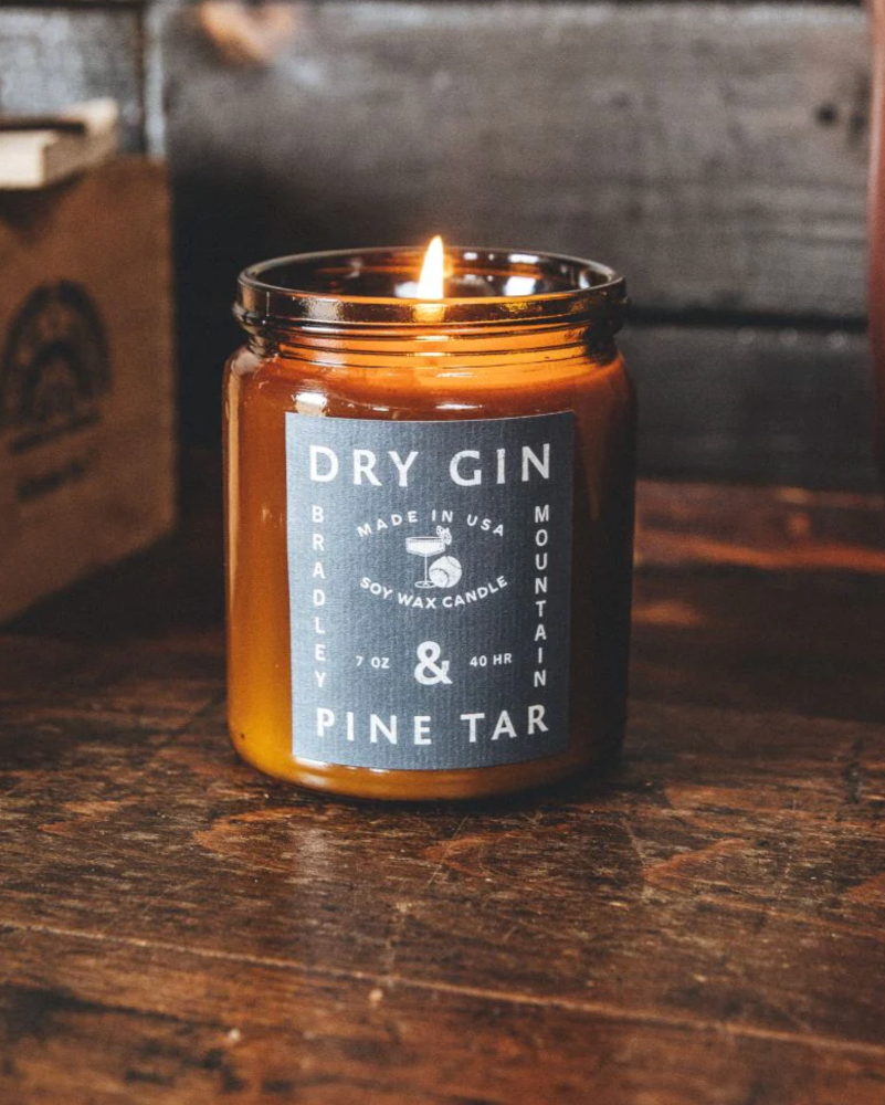 Candle in an amber jar with a label on a wooden surface