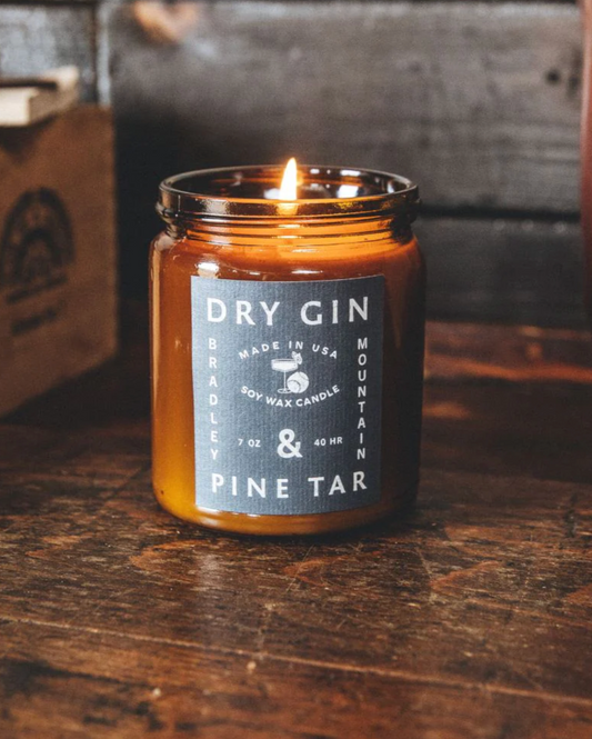 Candle in an amber jar with a label on a wooden surface