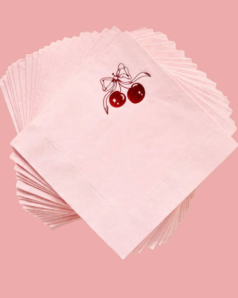 Stack of pink napkins with a cherry design on a light beige background