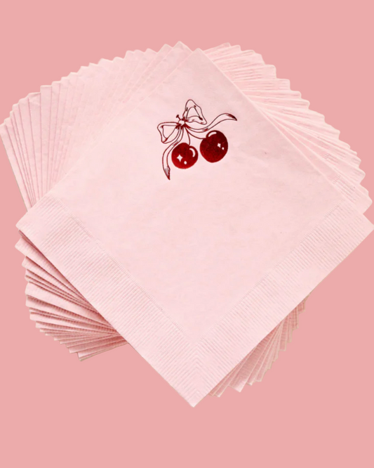 Stack of pink napkins with a cherry design on a light beige background