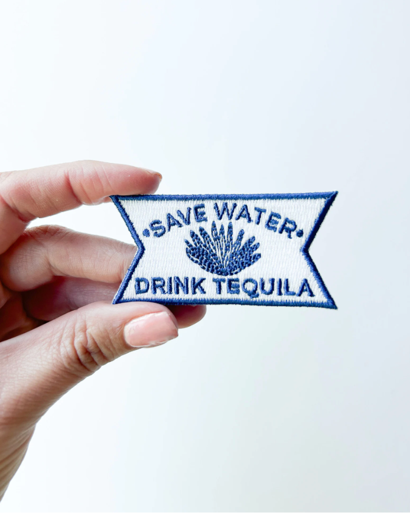 Embroidered patch with 'Save Water, Drink Tequila' text held by a hand on a white background
