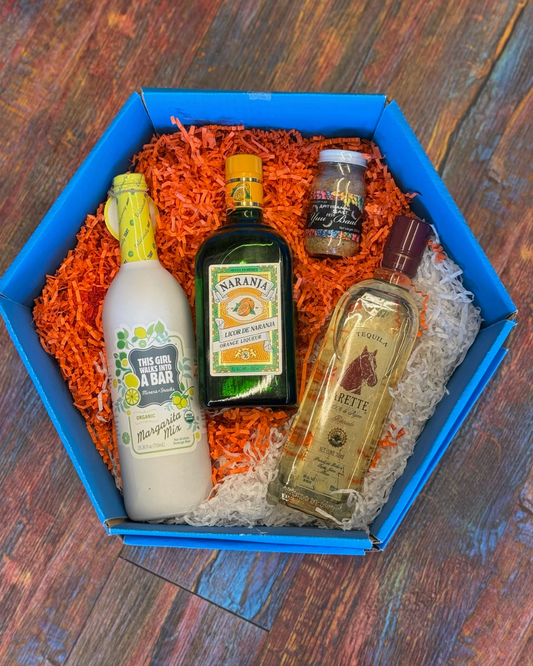 Four bottles of alcohol in a blue box on a wooden surface