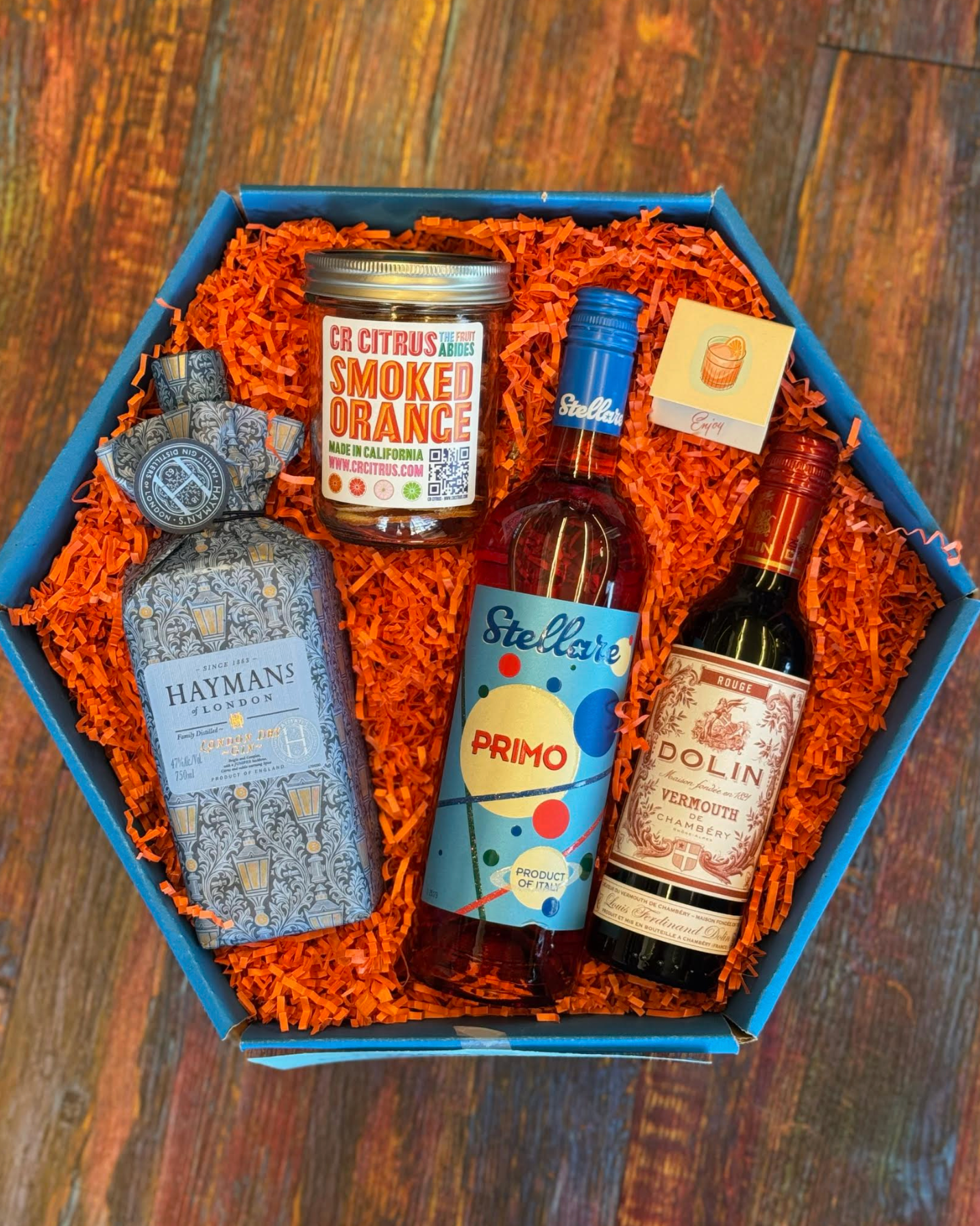 Gift box with bottles of alcohol and a jar on a wooden surface