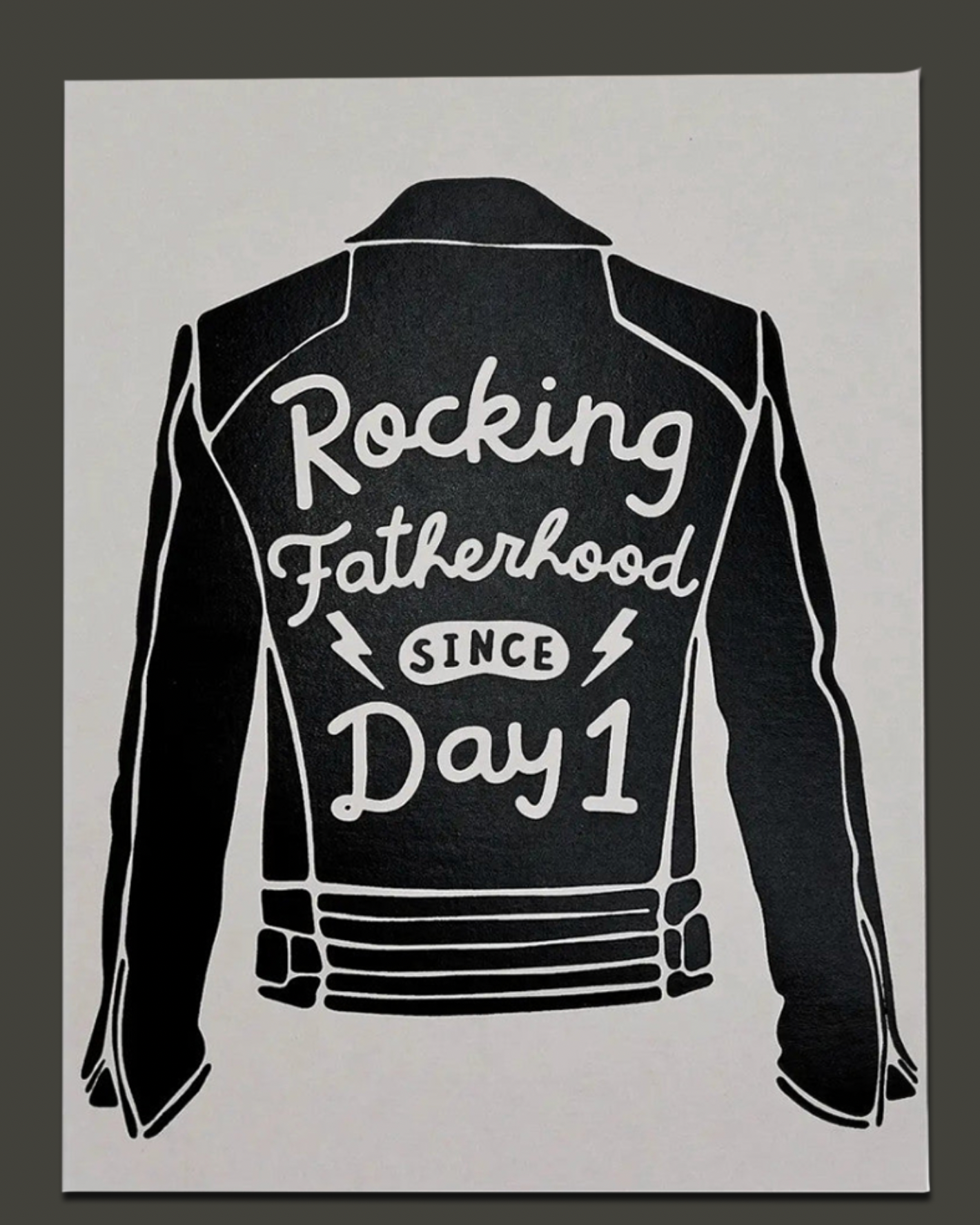 Black leather jacket with 'Rocking Fatherhood Since Day 1' text on a gray background