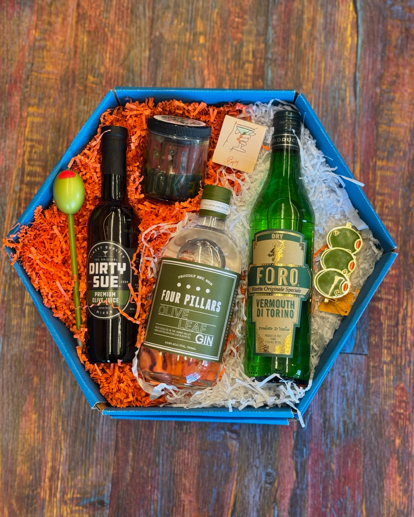 Gift box with bottles of gin and other items on a wooden surface