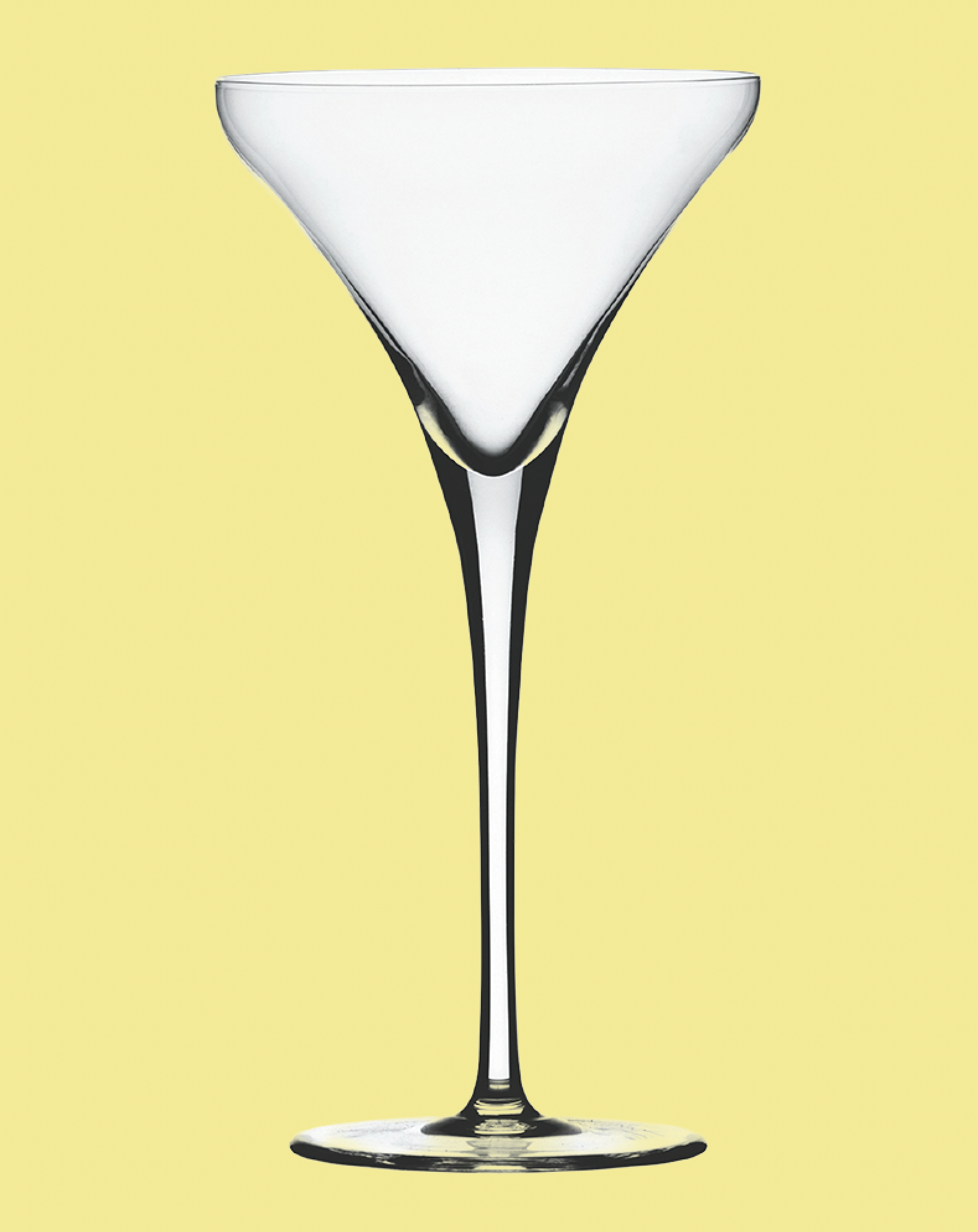 Clear martini glass on a light yellow background