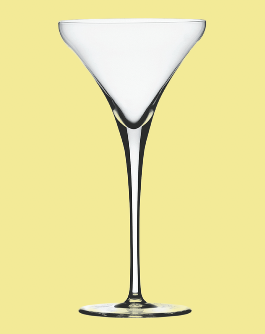 Clear martini glass on a light yellow background