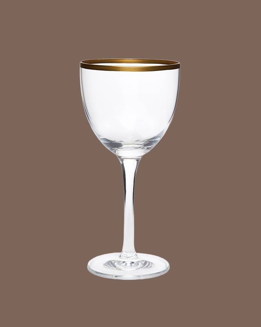 Clear wine glass with gold rim on a brown background