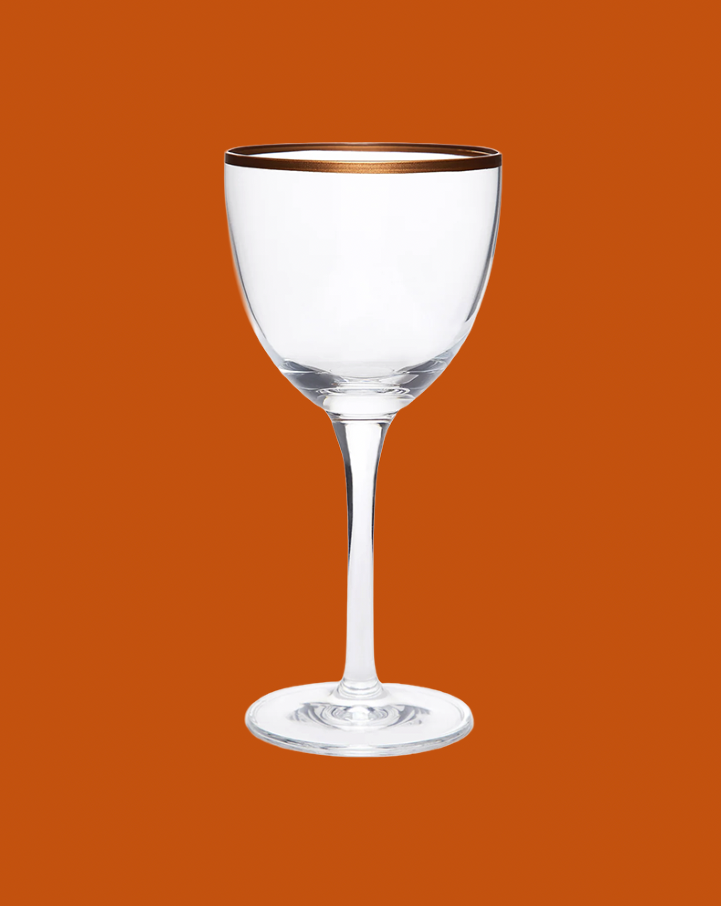 Clear wine glass with gold rim on an orange background