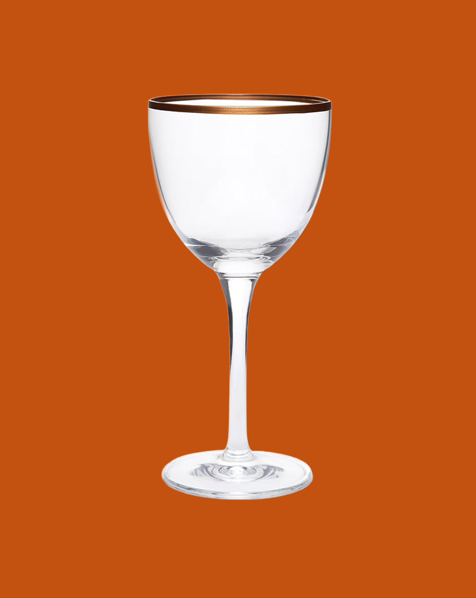 Clear wine glass with gold rim on an orange background