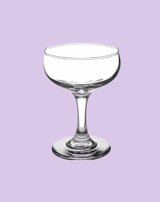 Clear glass coupe on a light purple background