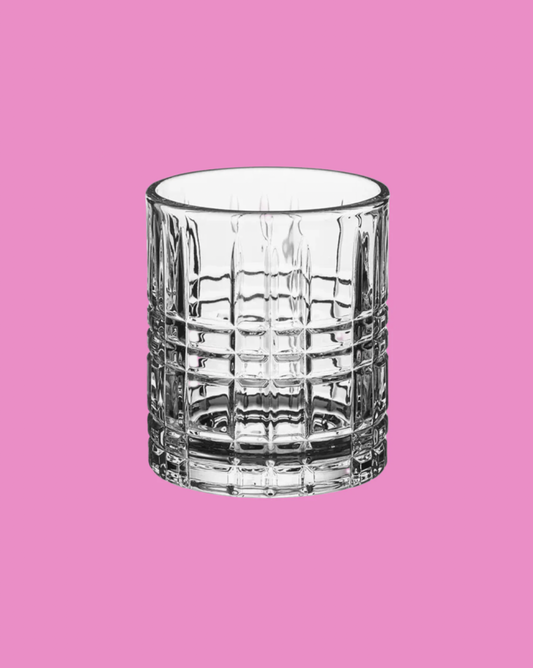 Clear glass tumbler on a pink background