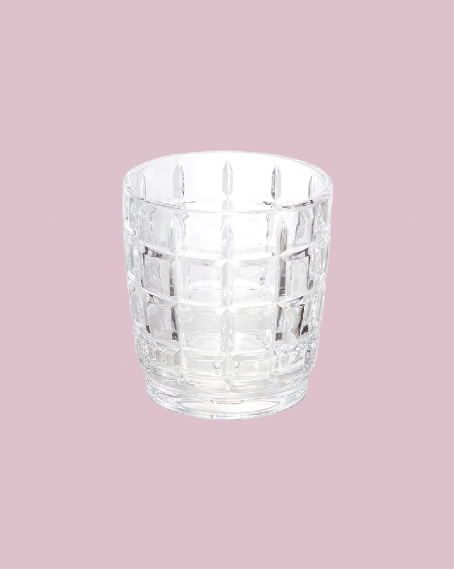 Clear glass tumbler with a textured pattern on a pink background