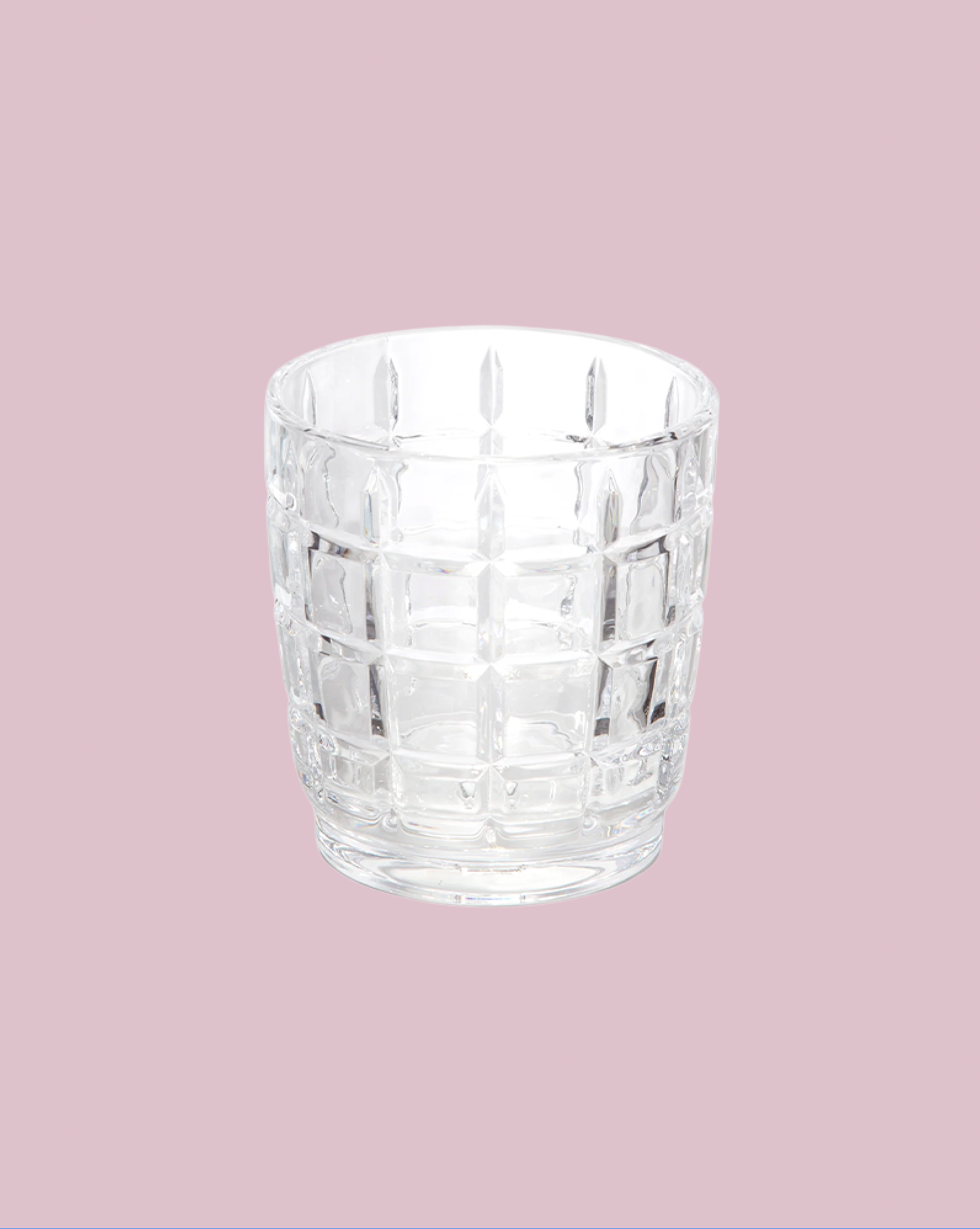 Clear glass tumbler with a textured pattern on a pink background