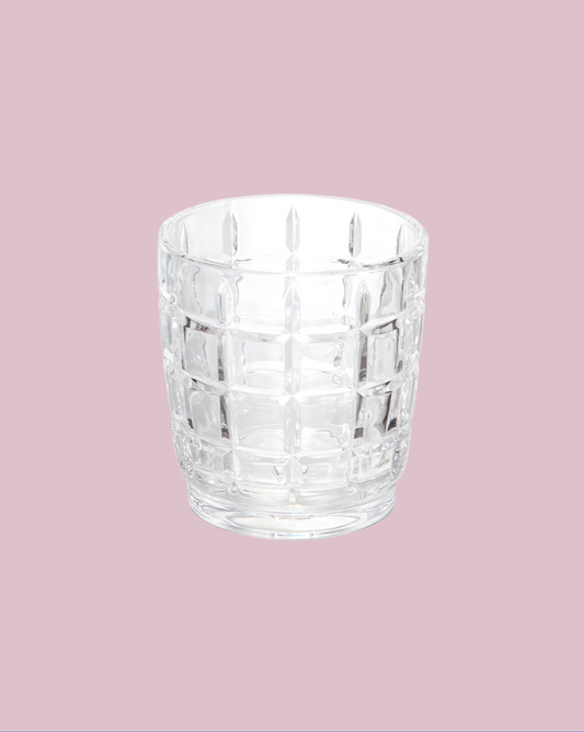 Clear glass tumbler with a textured pattern on a pink background