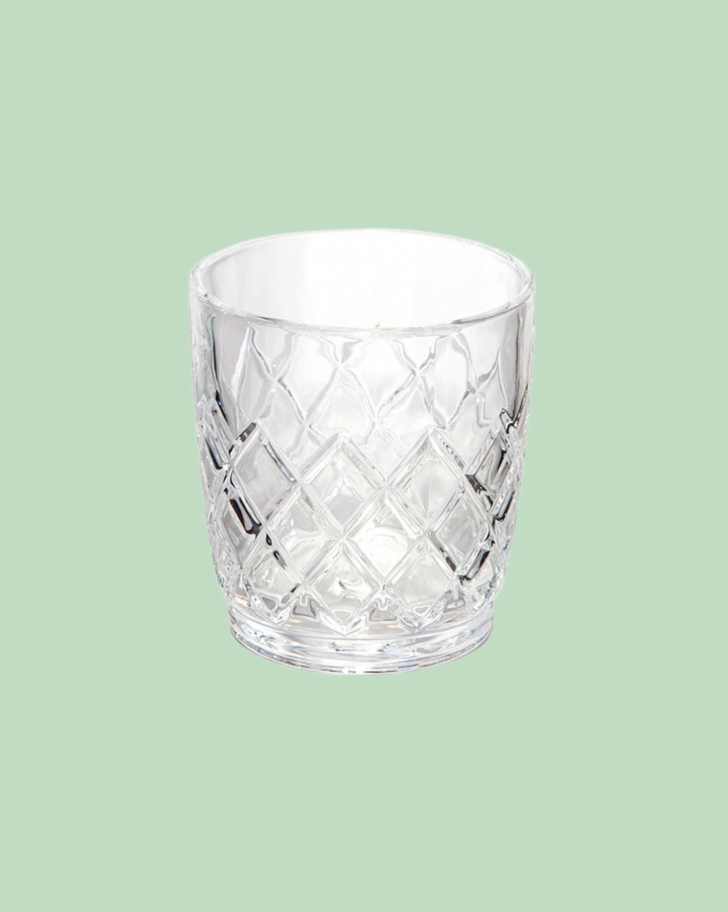 Clear glass tumbler with diamond pattern on a light green background
