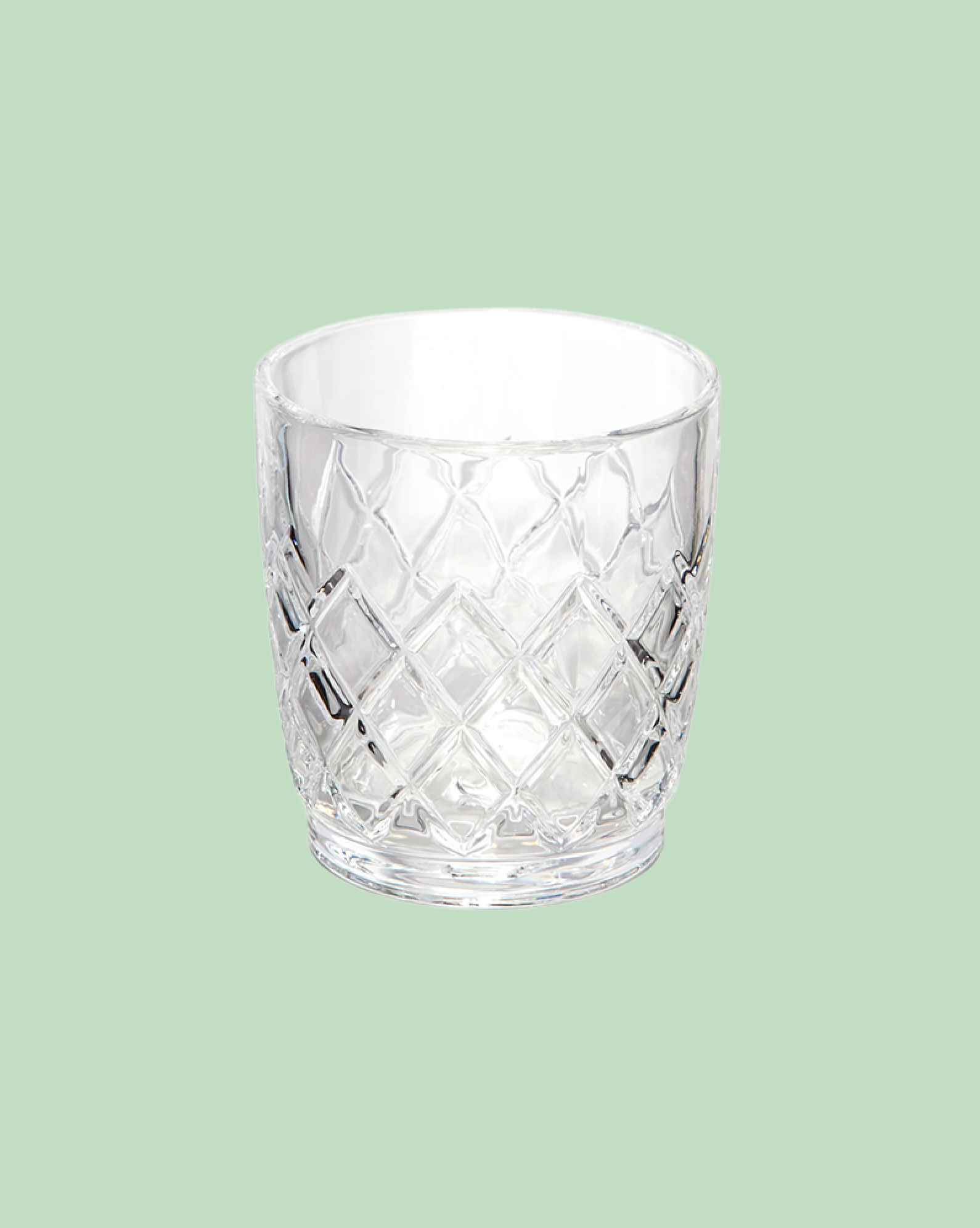 Clear glass tumbler with diamond pattern on a light green background