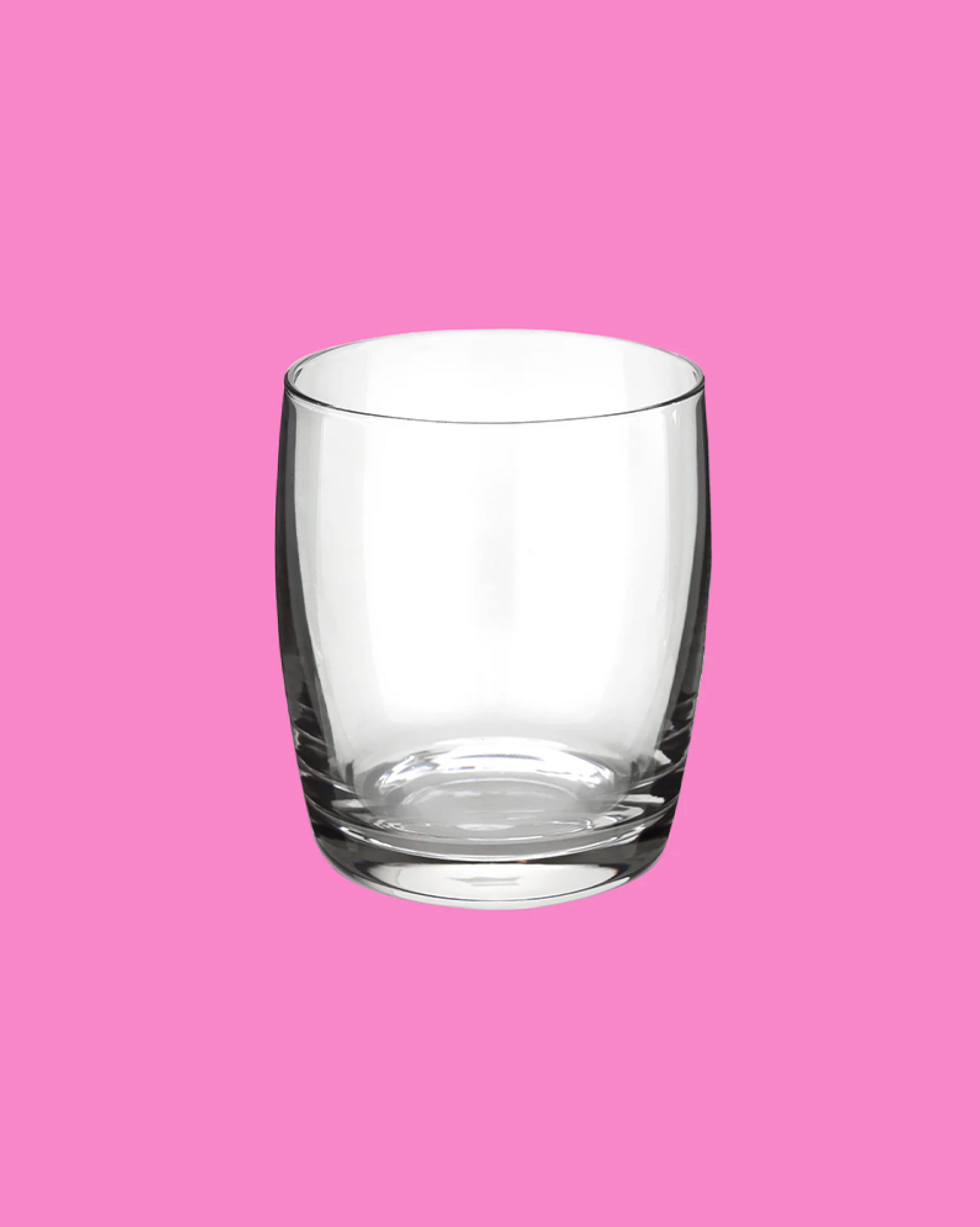 Clear glass tumbler on a pink background