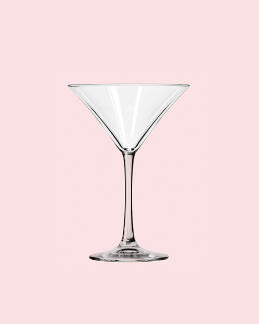 Clear martini glass on a pink background