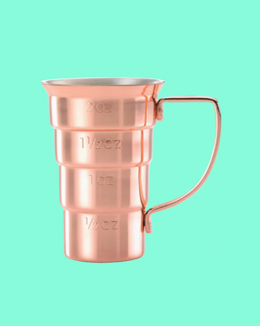 Copper measuring cup with measurement markings on a light green background