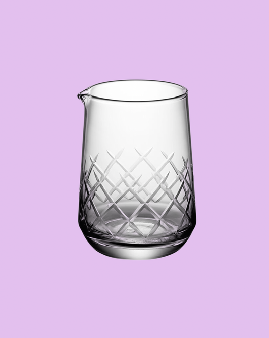 Clear glass pitcher with diamond pattern on a light purple background