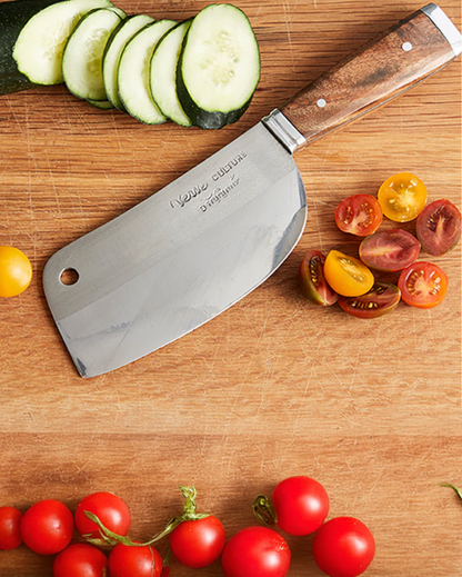 Knife with wooden handle on a cutting board surrounded by sliced cucumbers and tomatoes