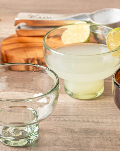 Two glasses with drinks, one filled and one empty, on a wooden surface.