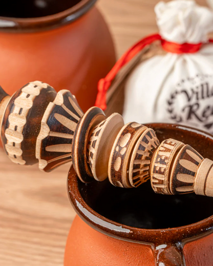 Honey dipper in a terracotta container with 'Villa Real' product in the background on a wooden surface.