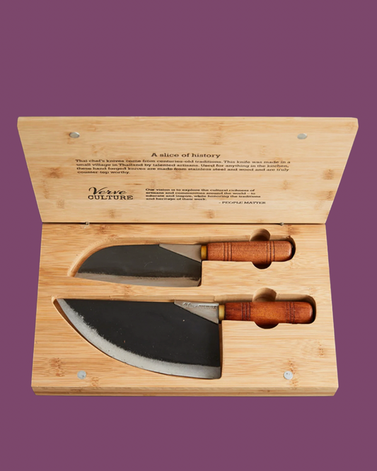 Two knives with wooden handles in a bamboo box on a purple background