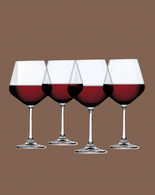 Four wine glasses filled with red wine on a brown background