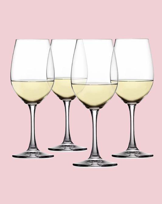 Four wine glasses filled with white wine on a pink background