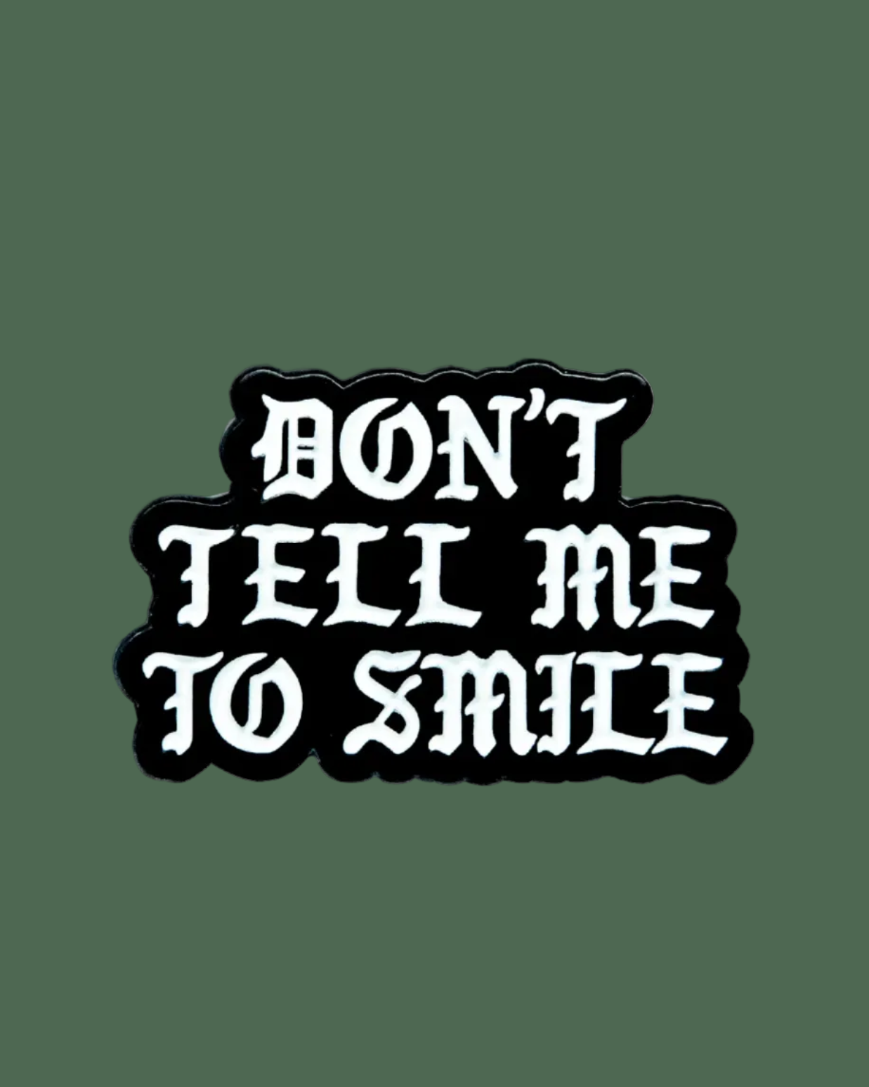 Black and white sticker with 'DON'T TELL ME TO SMILE' text on a white background