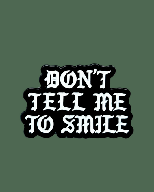 Black and white sticker with 'DON'T TELL ME TO SMILE' text on a white background
