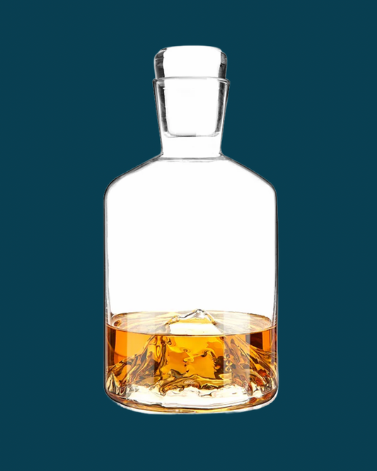Clear glass whiskey decanter with liquid on a dark blue background