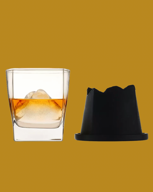 Clear glass with ice and liquid next to a black coaster on a yellow background