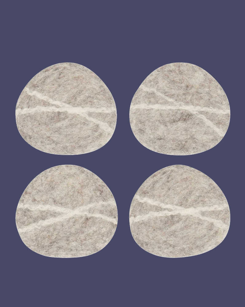 four pebble shaped wool felt coaster on a purple background