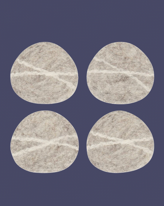 four pebble shaped wool felt coaster on a purple background